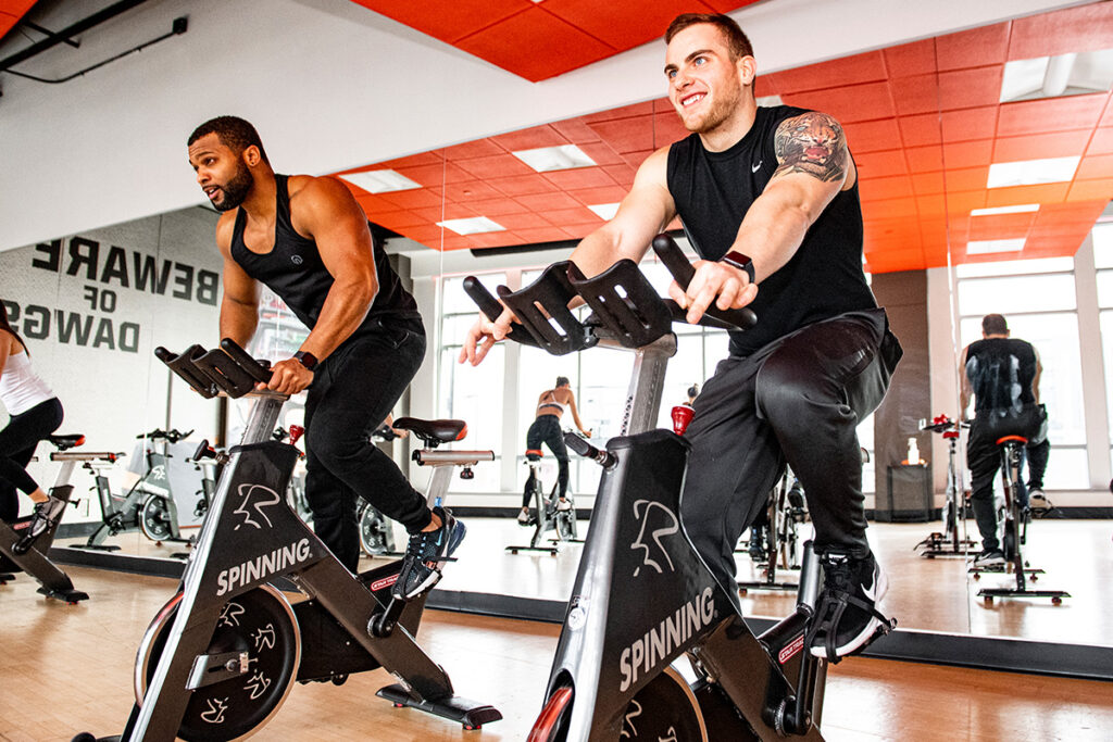 People are riding on exercise bikes at a Browns Fit gym.