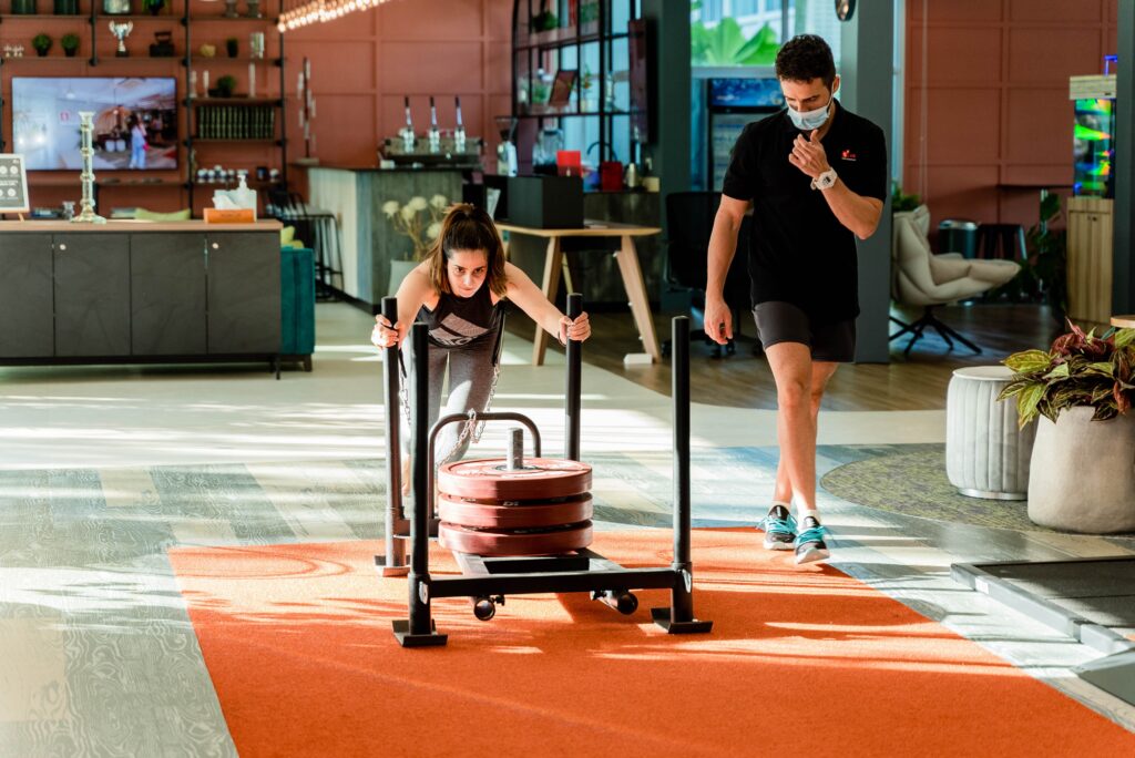Female athlete performing a heavy sled push at Browns Fit gym during a hyrox vs crossfit training block.